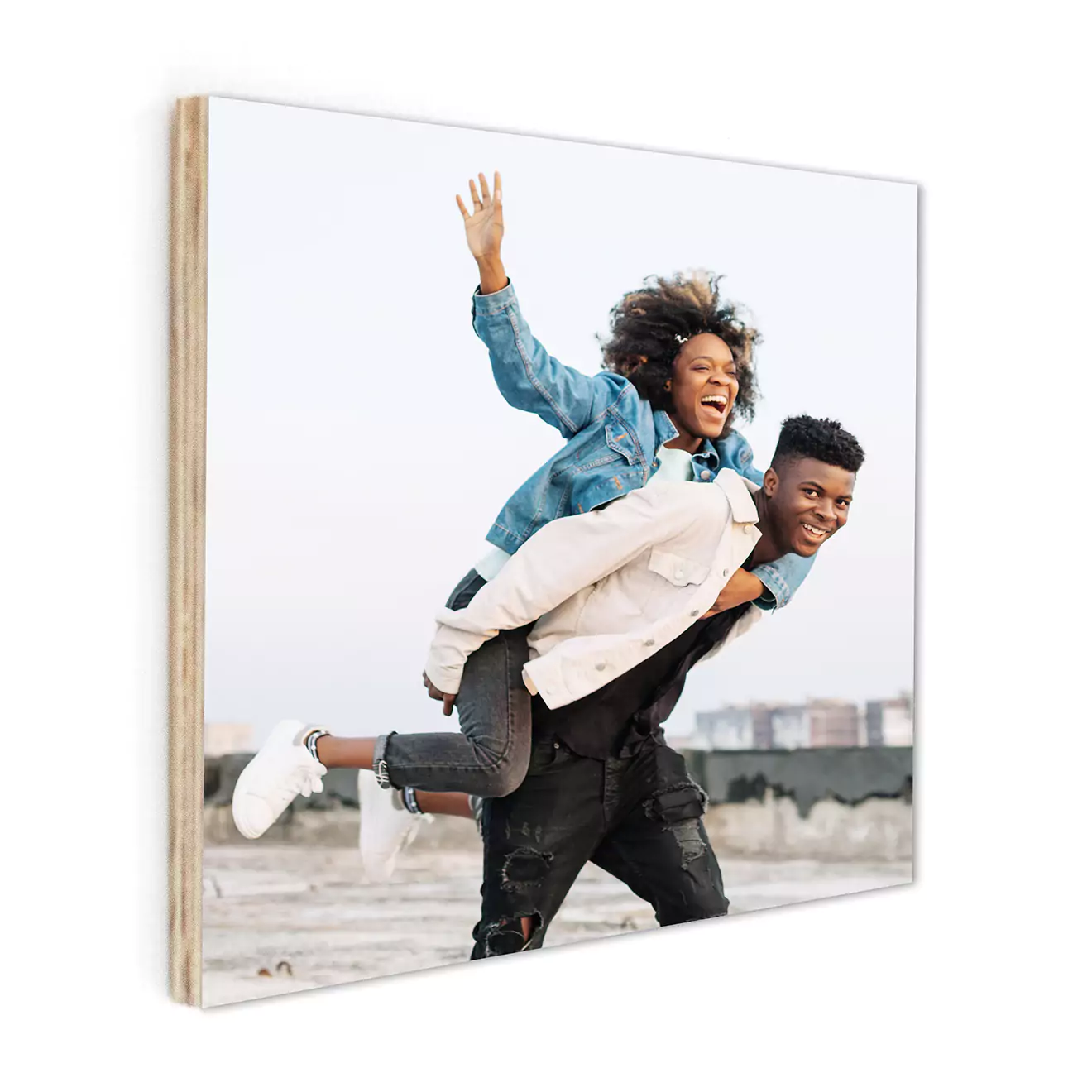 Personalised photo book with a cover image of a joyful couple having fun outdoors. The man carries the woman on his back as they both smile and laugh. The photo book features a clean, modern design with a sturdy, light-coloured spine. Ideal for gifts, including Christmas and Valentine''s Day.