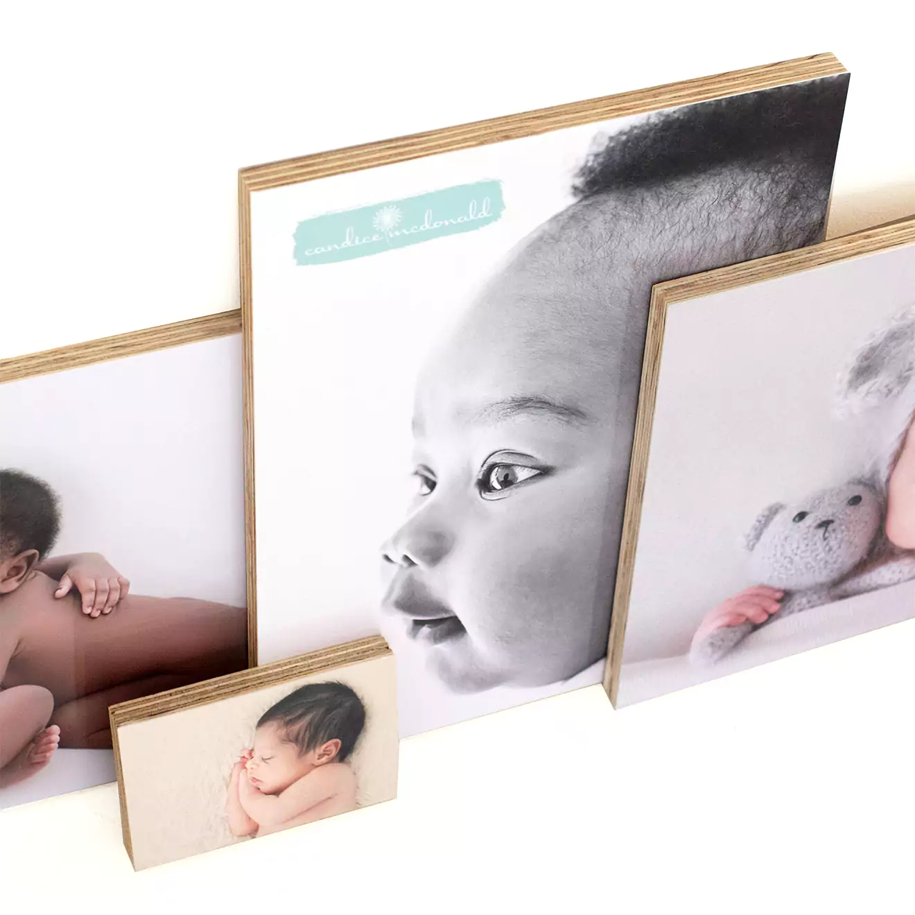 A set of four wooden photo blocks featuring black and white and colour images of a baby. The blocks vary in size, with the largest displaying a close-up of the baby's face, and the others showing different baby poses. Ideal for personalised gifts, baby shower gift ideas, or home decor.