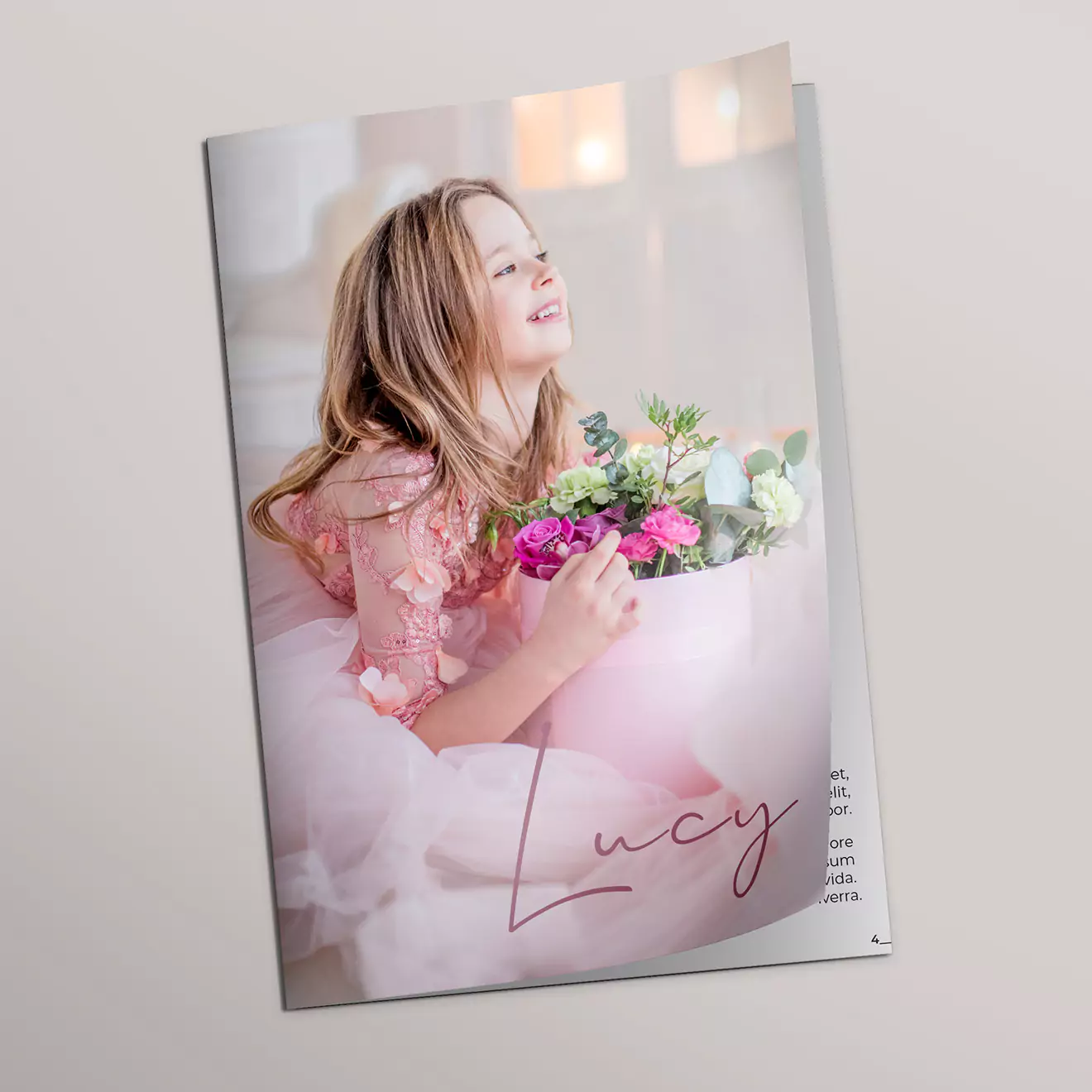 Personalised photo book featuring a young girl holding a bouquet of flowers, with the name "Lucy" written in elegant script on the cover. The photo book has a soft, pastel colour scheme and a glossy finish, making it a perfect gift for special occasions such as birthdays or baby showers.