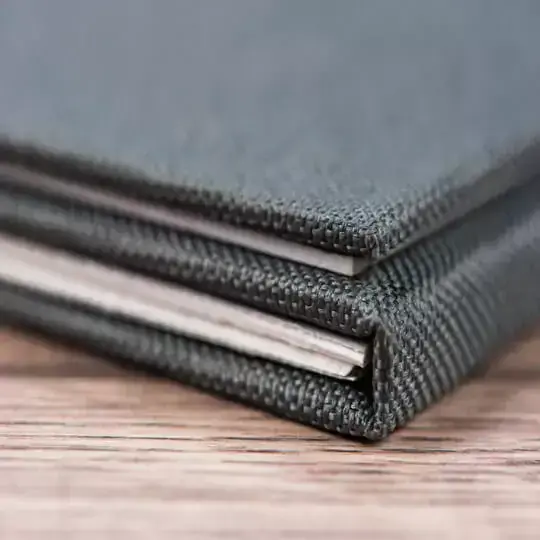 Close-up image of a grey fabric-covered photo book with a textured cover. The book is closed, showing the neatly bound edges and the thickness of the pages. The photo book is resting on a wooden surface, highlighting its high-quality craftsmanship. Ideal for personalised gifts in South Africa.