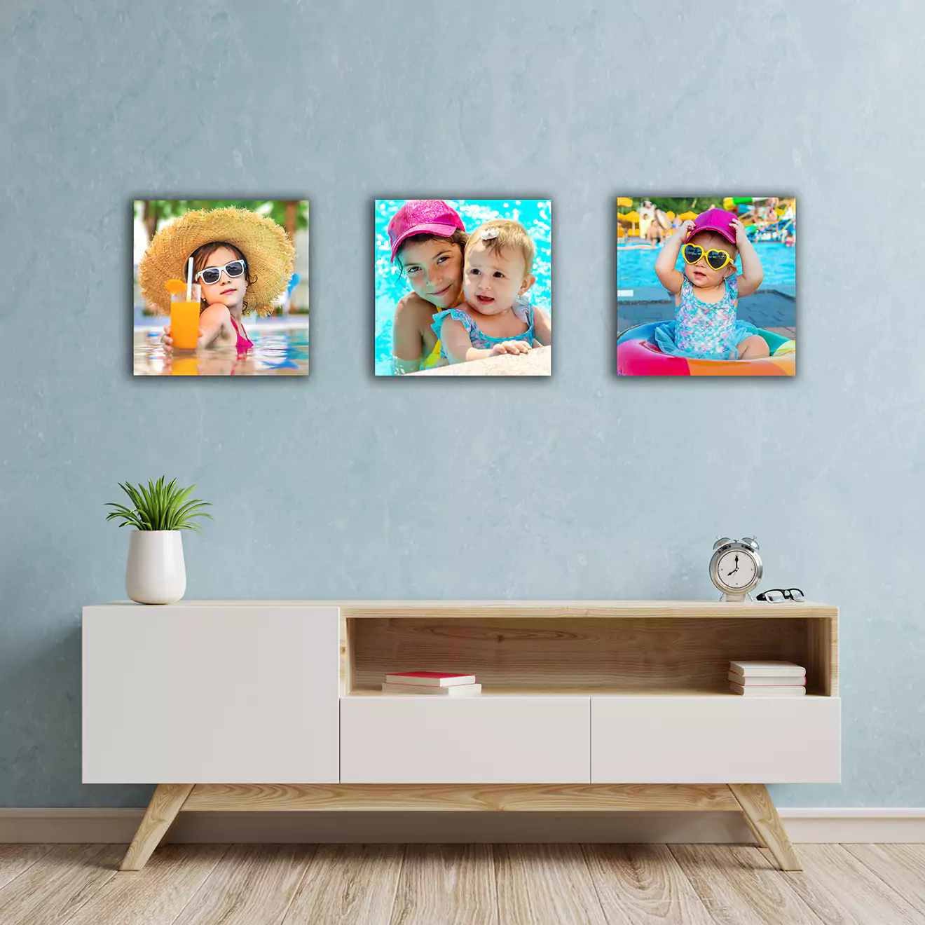 Living room with a modern white console table and three square photo canvases on the wall above it, each featuring children enjoying a sunny day by the pool.