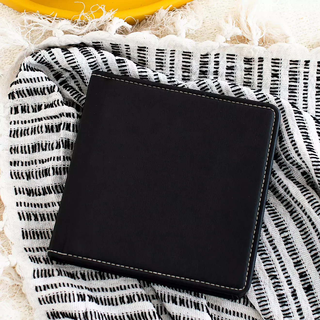 Elegant black photo album with white stitching, resting on a black-and-white striped fabric. Ideal for personalised gifts in South Africa, this photo album is perfect for preserving memories and makes a thoughtful gift for occasions such as Christmas, Valentine''s Day, or baby showers.