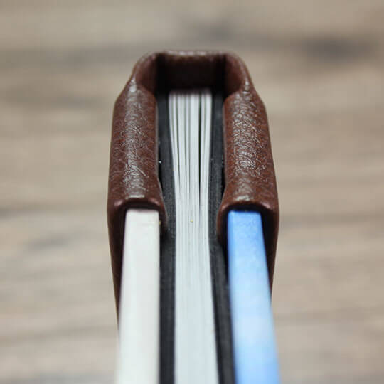 Close-up view of a photo album with a brown leather spine, showcasing the thickness and quality of the pages. Ideal for personalised gifts, photo books, and special occasions like Christmas or Valentine's Day.