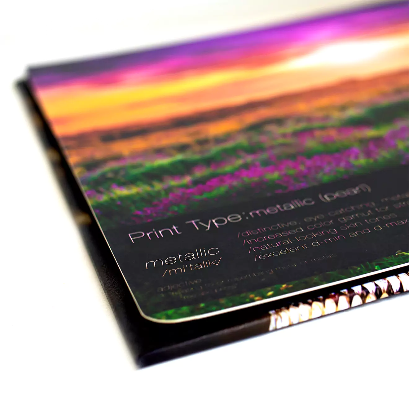 Close-up of a photobook with a metallic finish, showcasing a vibrant, colourful landscape image on the cover. The print type is labelled as metallic, providing a glossy and reflective surface. Ideal for personalised gifts, photo albums, and special occasions like Christmas or Valentine's Day.