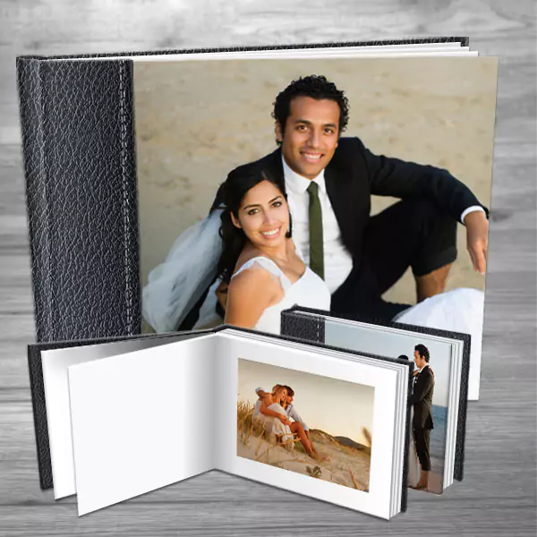 Elegant black leather-bound photo album featuring a wedding couple on the cover. The album is open to display high-quality printed photos inside, ideal for preserving precious memories. Perfect for wedding gifts, personalised gifts in South Africa, or photo books.