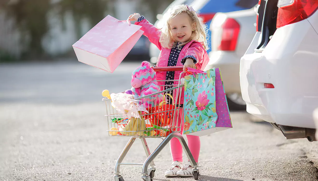 Very young little girl pushing a tiny trolley filled with numerous purchases - banner