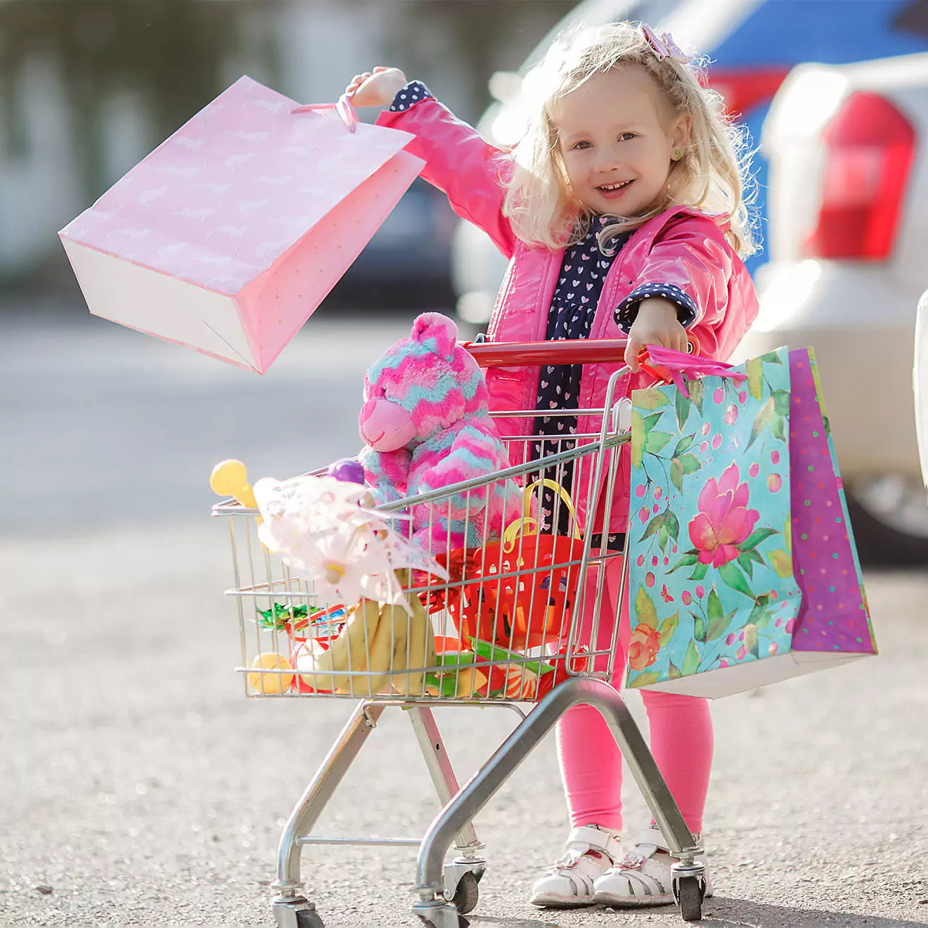 Very young little girl pushing a tiny trolley filled with numerous purchases