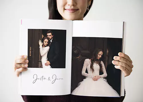 Person opening a photo book featuring a beautifully designed page with a bride and groom