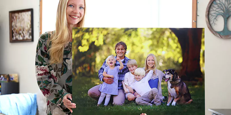 Woman holding a canvas print of her family, including her pet, showcasing a cherished family moment