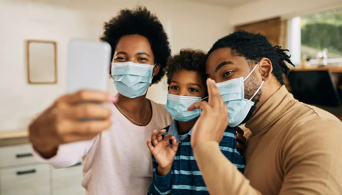 Family taking a selfie with masks on during the COVID-19 pandemic - banner