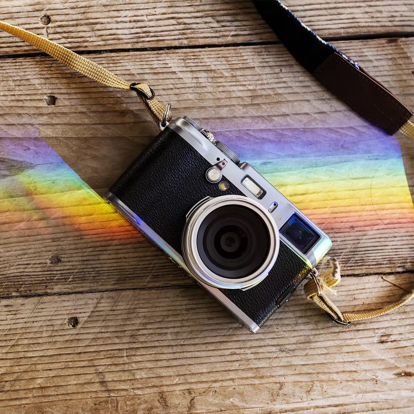 Vintage-style camera on a wooden deck with a beautiful rainbow in the background