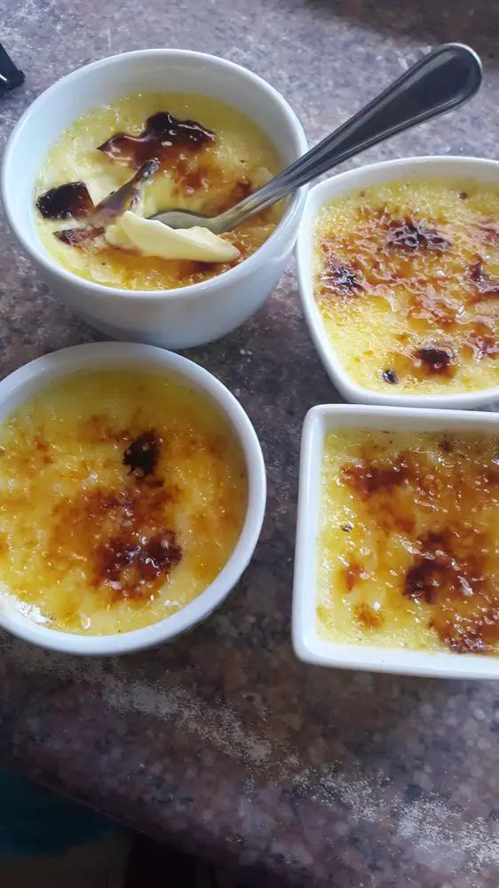 Four crème brûlées in different shaped cups, each showcasing its caramelised top and creamy texture