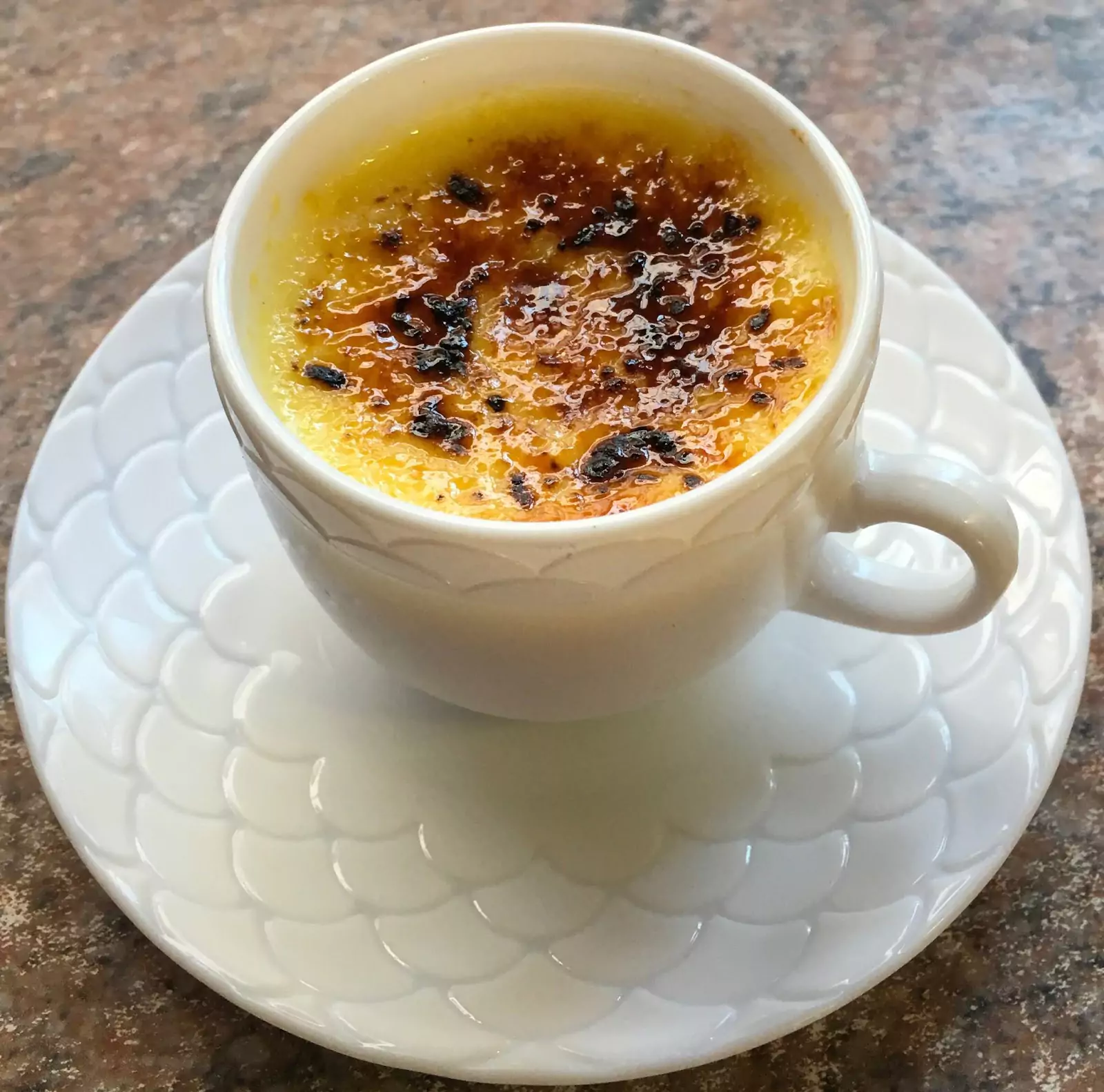 Crème brûlée served in a teacup, showcasing its creamy texture and caramelised top