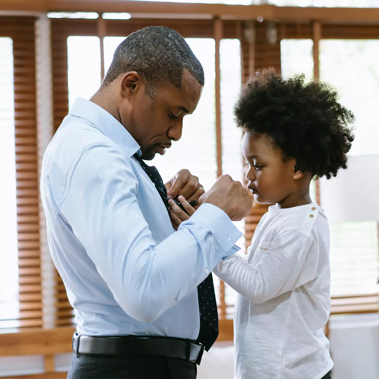 Child helping dad tie his tie, a heartwarming Father's Day moment