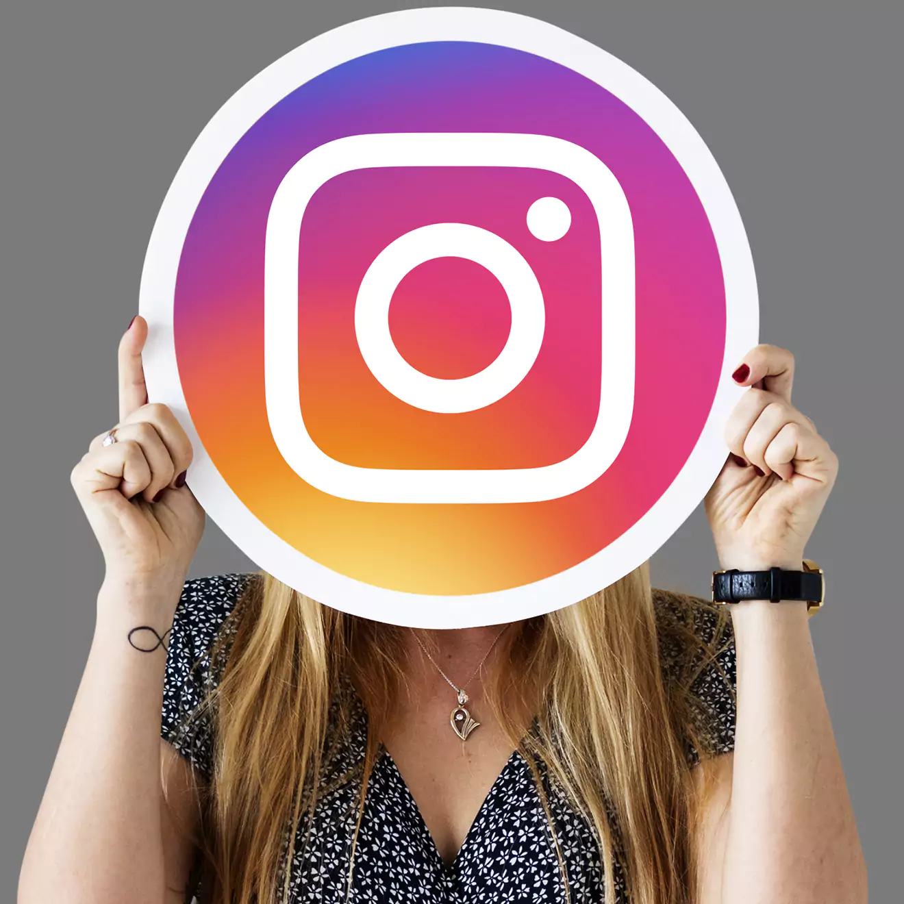 Woman holding up the Instagram logo, representing social media engagement