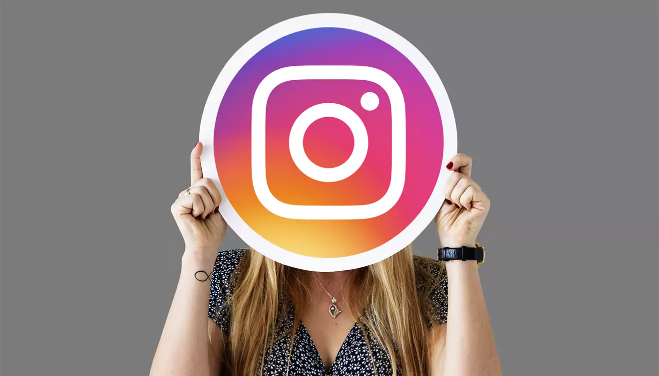 Woman holding up the Instagram logo, representing social media engagement - banner