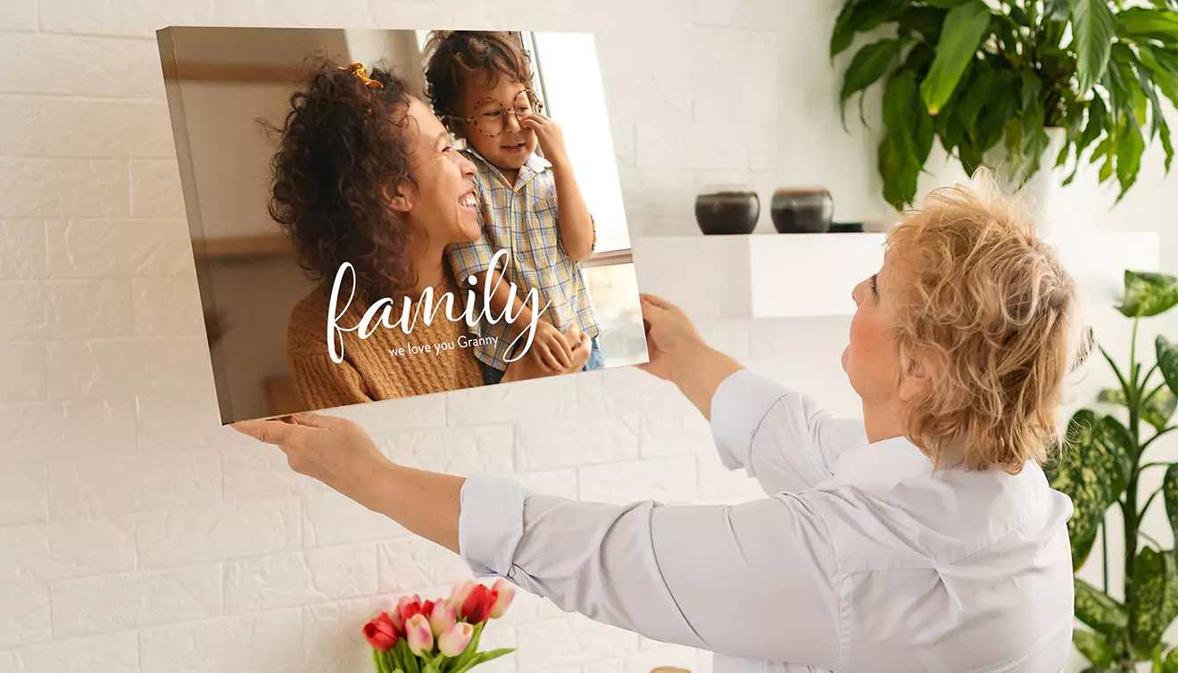 Mom hanging a personalised family canvas on her wall, adding a personal touch to her home decor - banner