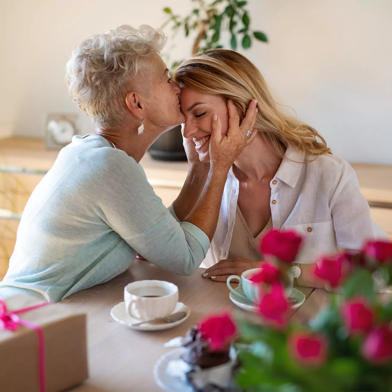 Daughter being kissed by her mother after receiving a personalised Mother's Day gift, capturing a tender and loving moment