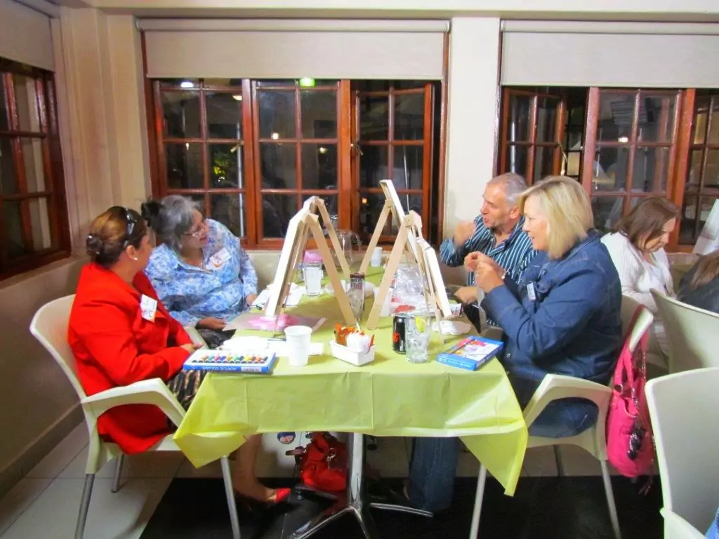 Person adding the finishing touches to their painting on a canvas at a lively evening event