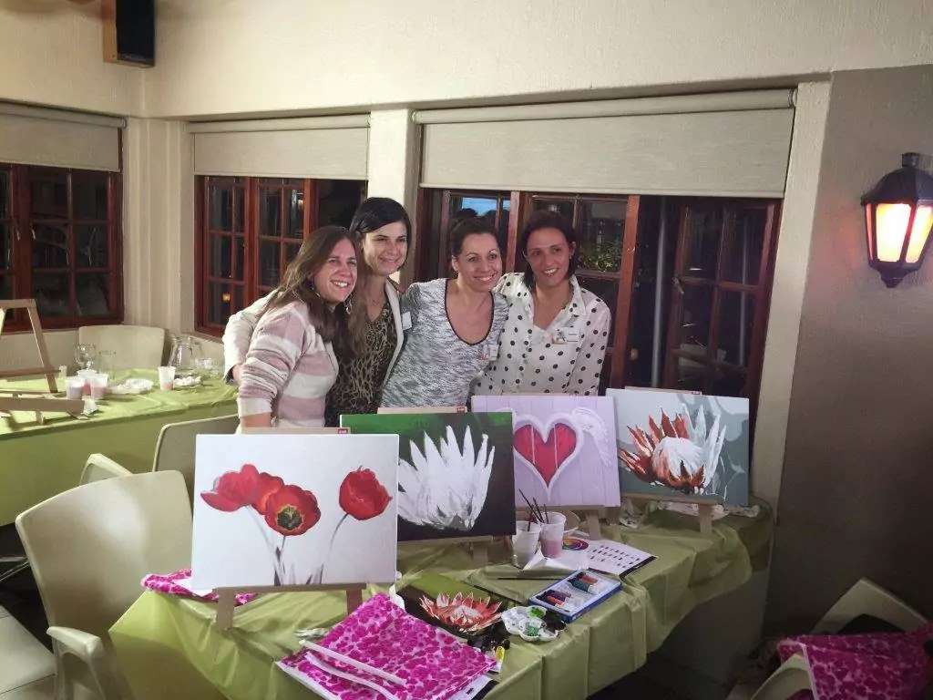 Attendee focused on their artwork, painting on a canvas during a vibrant evening event