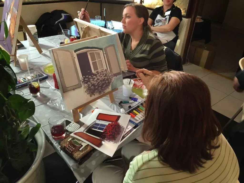 Guest painting on a canvas at an evening event, immersed in the creative process