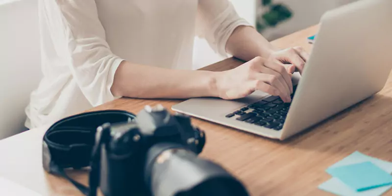 Person ordering their photos on a PC, with a camera placed next to the computer for easy access - banner