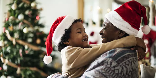 Grandmother and granddaughter wearing Christmas hats, smiling at each other in a heartwarming holiday moment - banner