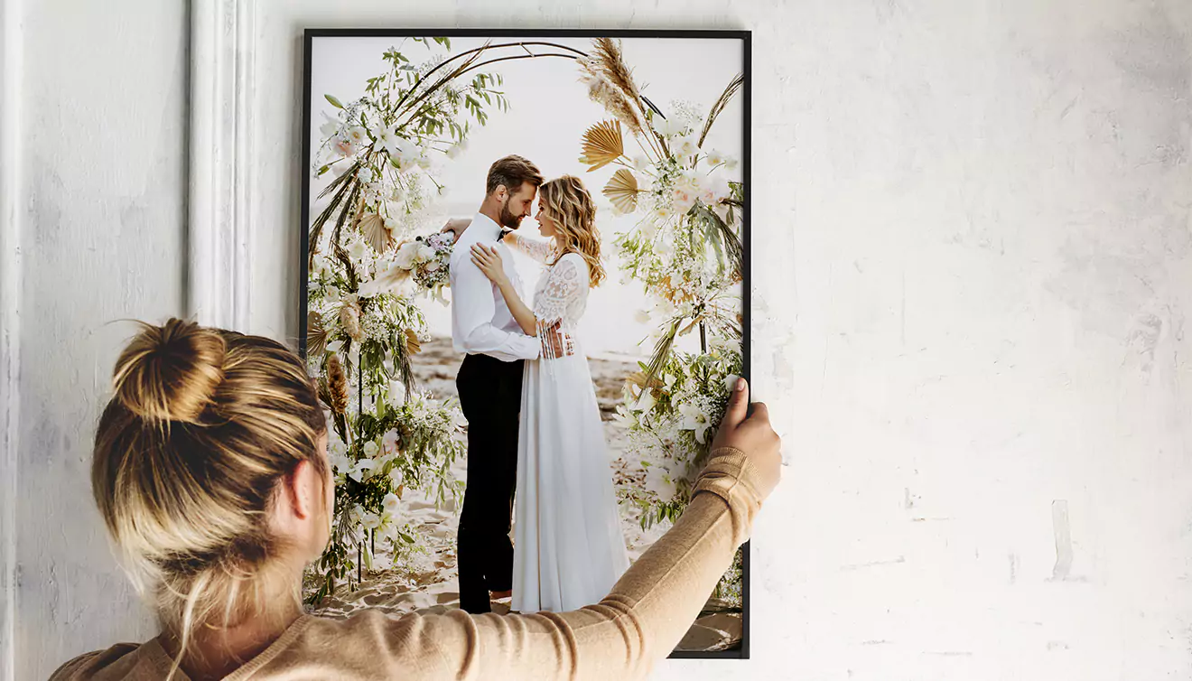 Woman hanging a beautiful framed canvas on the wall, adding a personal touch to her home decor - banner