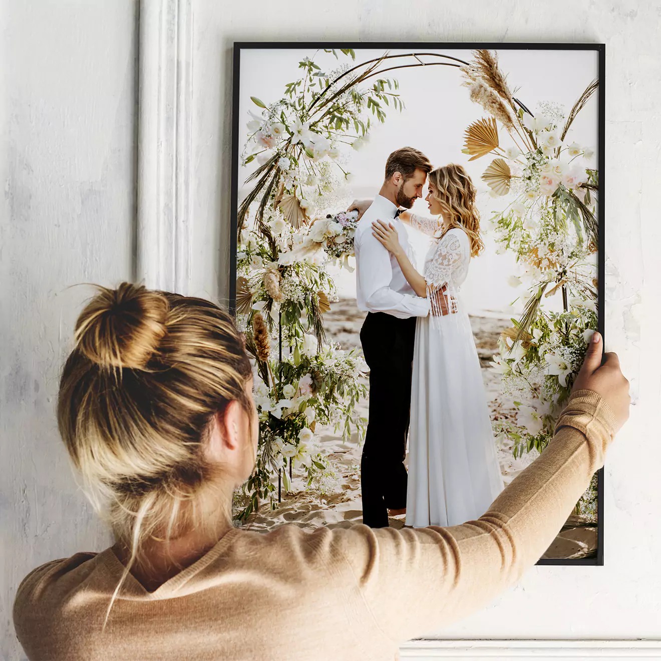 Woman hanging a beautiful framed canvas on the wall, adding a personal touch to her home decor