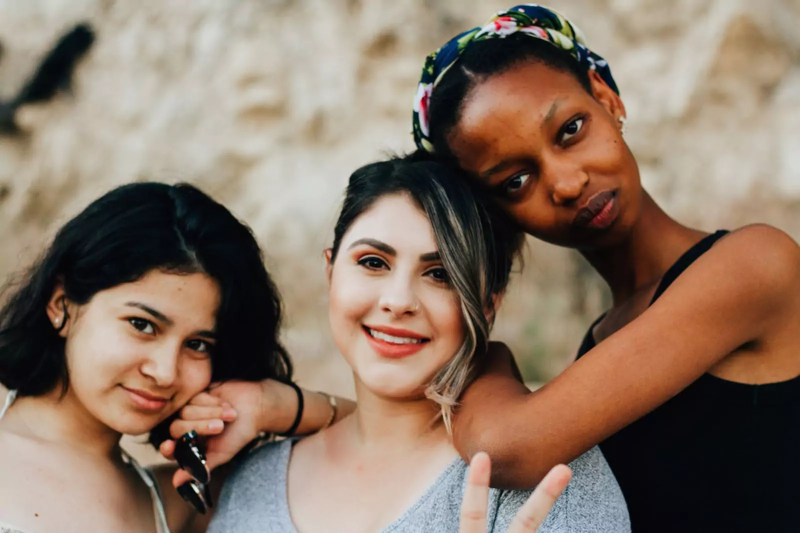 Three young women smiling at the camera, sharing a joyful moment together